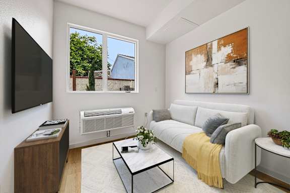 A living room with a grey couch, a coffee table, a flat screen TV, and a painting on the wall.