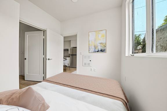 A bedroom with a bed, a painting, and a window.