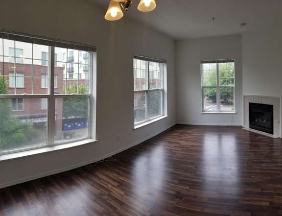 A large empty room with wooden floors and a fireplace.