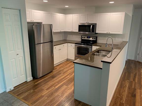 A kitchen with a stainless steel refrigerator, microwave, and oven.