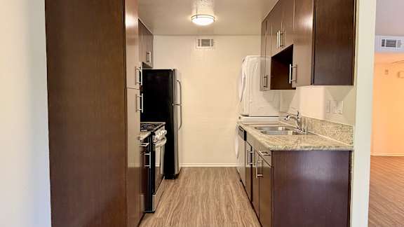 A kitchen with a refrigerator, dishwasher, and sink.