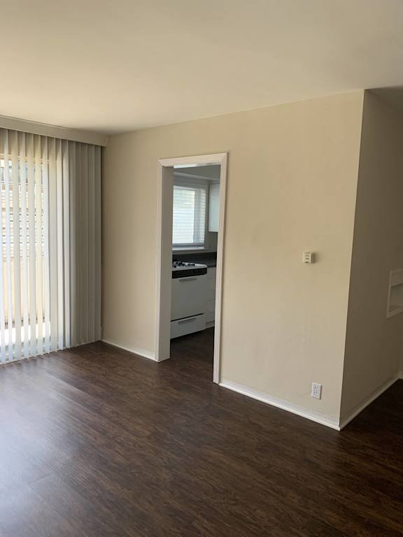A room with a wooden floor and a window with blinds.