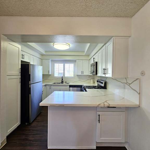 A kitchen with white cabinets and a black fridge.