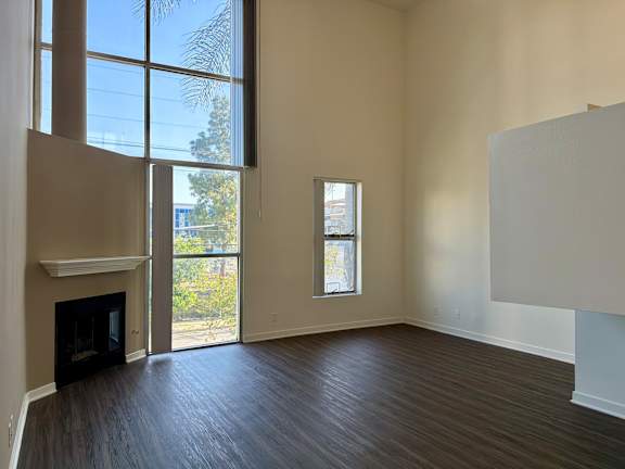 A large empty room with a fireplace and a window.