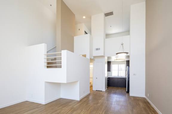 A white interior of a 1-bedroom LOFT with a kitchen in the background.