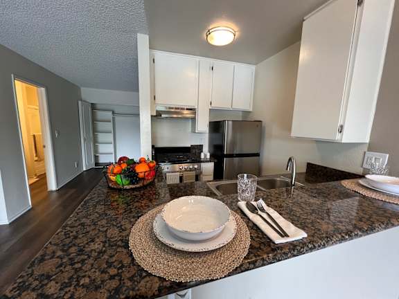 A kitchen with a granite countertop and a bowl of fruit on it.