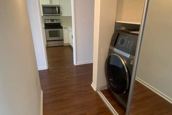 A modern kitchen with a washing machine in the corner.