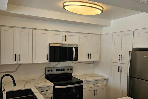 A kitchen with white cabinets and black appliances.