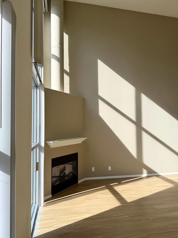 A room with a fireplace and a large window letting in sunlight.