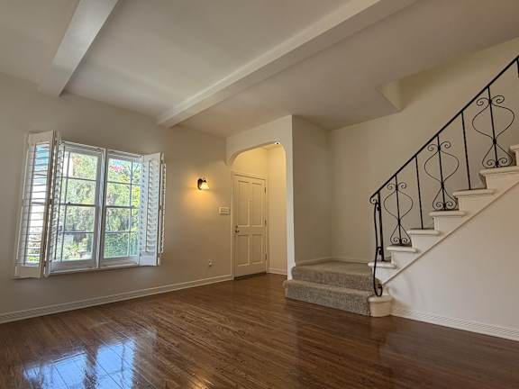 A room with wooden floors and a staircase with black metal railings.