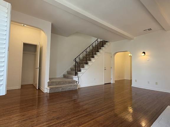 A spacious room with a staircase and wooden flooring.