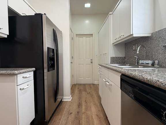 A kitchen with black appliances and white cabinets.