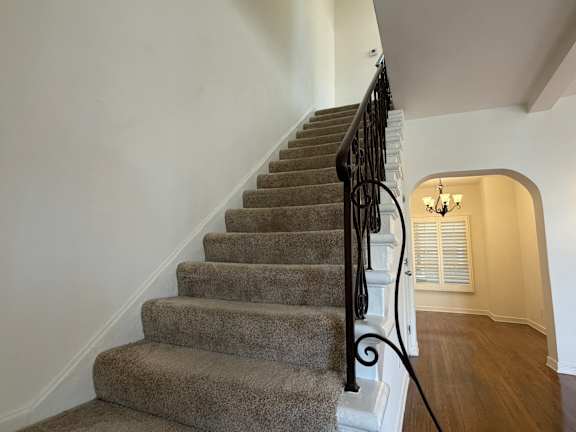 A staircase with a metal railing and a chandelier in the background.