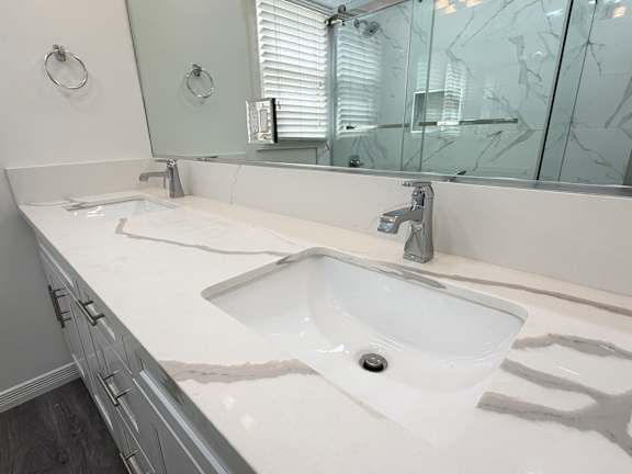 A white sink with a silver faucet is in the middle of a marble countertop.