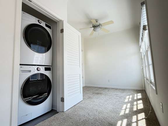 A white washer and dryer in a laundry room with a ceiling fan.