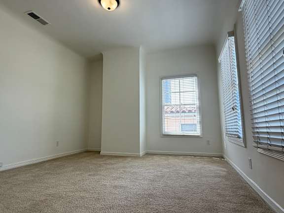 A room with a window and a carpeted floor.