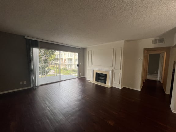 an empty living room with wood floors and a fireplace
