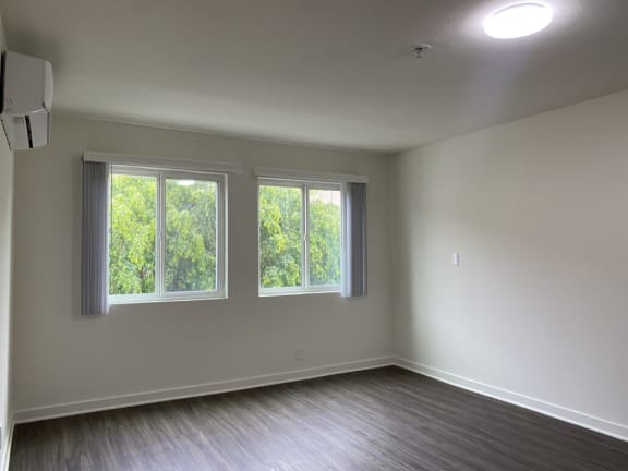 an empty living room with three windows and wood floors