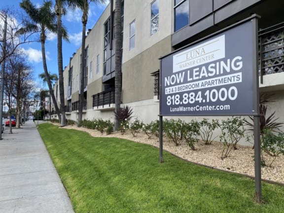 a now leasing sign in front of an apartment building