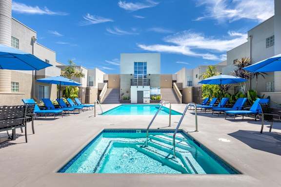 A swimming pool surrounded by lounge chairs and umbrellas.