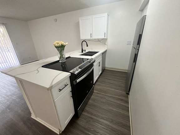 A kitchen with white cabinets and a black countertop.