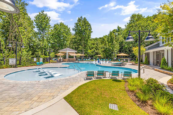 a resort style swimming pool with chairs and umbrellas