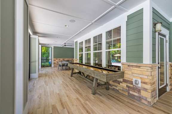 a game room with a shuffleboard table and windows