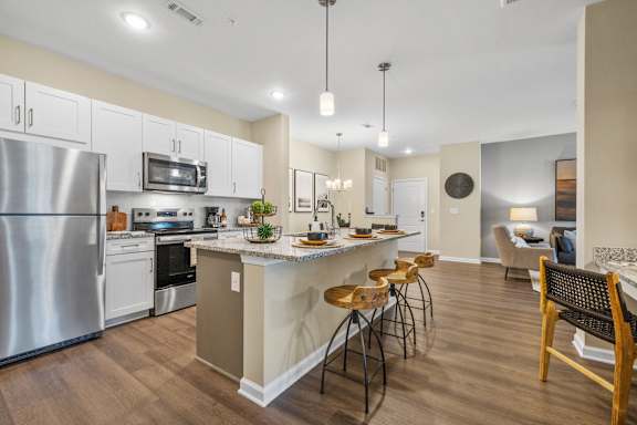 an open kitchen and living room with an island and stools