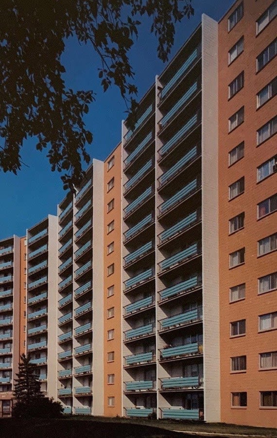 a row of tall apartment buildings with trees in the foreground