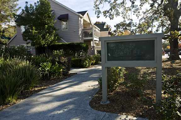 a sign in front of a house with a sidewalk