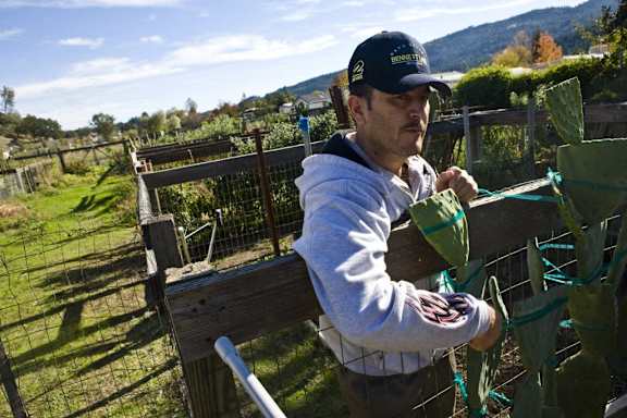 a man standing next to a fence holding a watering can