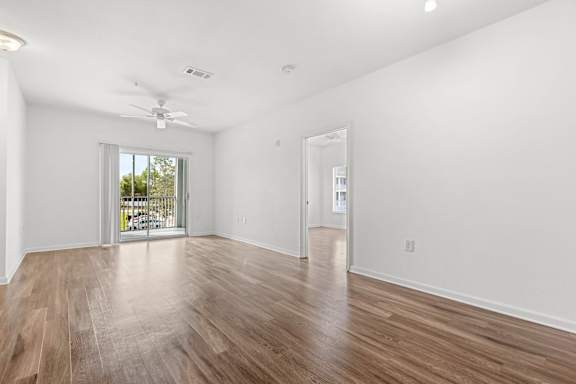A room with a ceiling fan and sliding glass doors.