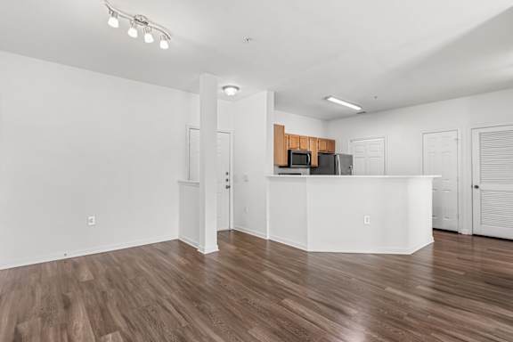 A white reception desk with a microwave on top in a room with wooden flooring.