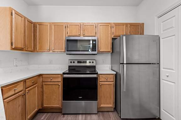 A kitchen with wooden cabinets and a stainless steel refrigerator.