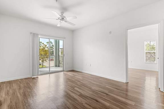 A room with a ceiling fan and sliding glass doors.