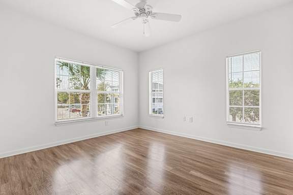 A room with a ceiling fan and two windows.