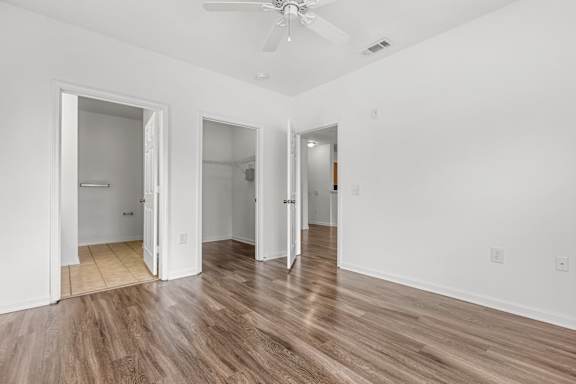 A room with a ceiling fan and wooden flooring.