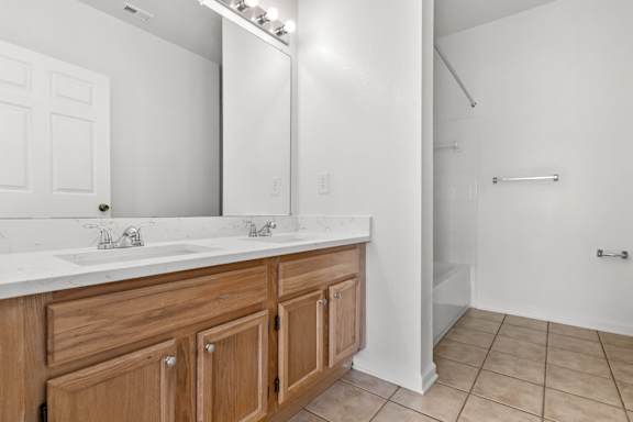 A bathroom with a white counter top and wooden cabinets.
