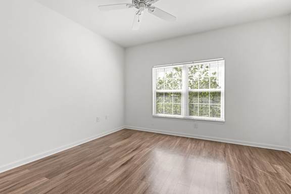 A room with a ceiling fan and a window with blinds.