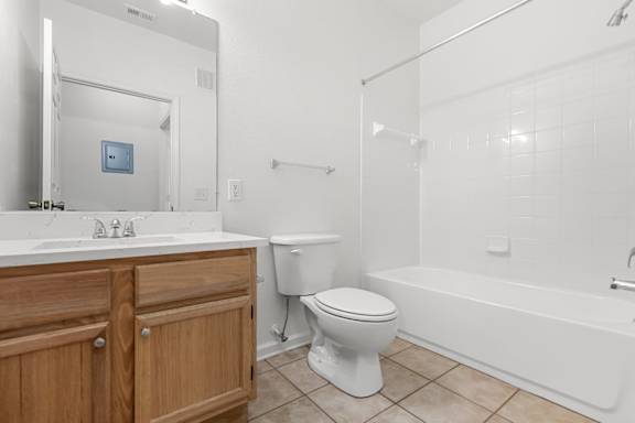 A white toilet sits in a bathroom next to a white bathtub.