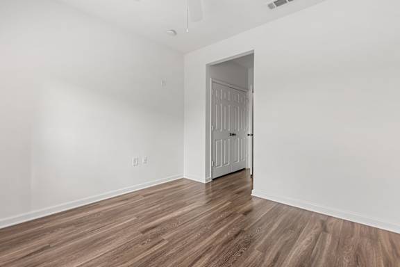 A room with a white door and wooden flooring.