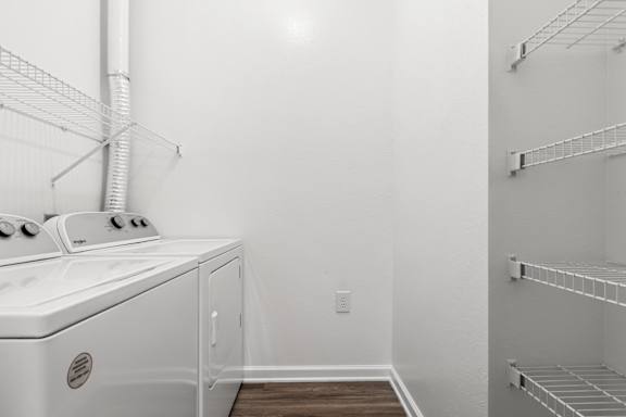 A white oven and microwave in a kitchen with white walls and wood flooring.