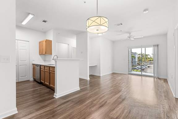 A well-lit, spacious kitchen with wooden floors and white walls.