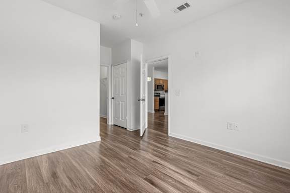 A room with white walls and wooden flooring with a doorway leading to another room.