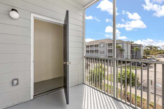 A balcony with a glass door leading to a building.