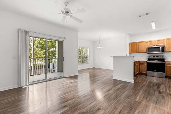 A spacious kitchen with wooden floors and a ceiling fan.