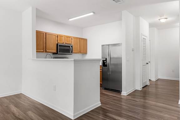 A kitchen with wooden cabinets and a stainless steel refrigerator.