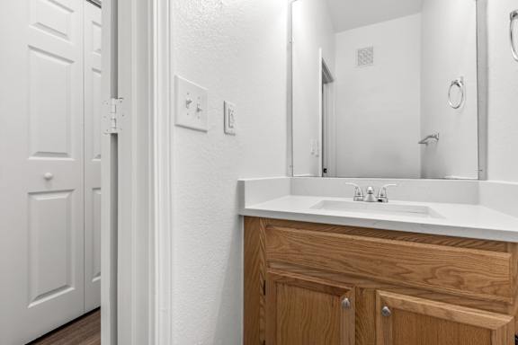 A white bathroom with a wooden vanity and a mirror.