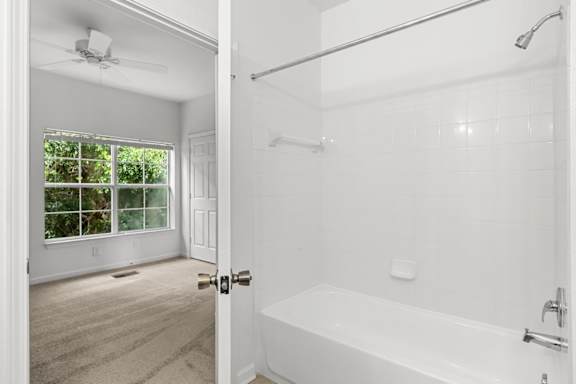 A white bathroom with a window and a bathtub.
