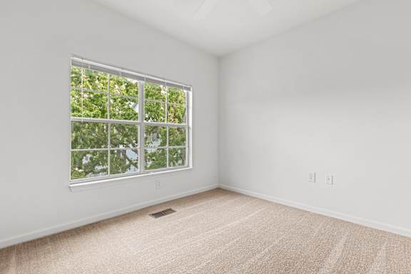 A room with a window and carpeted floor.